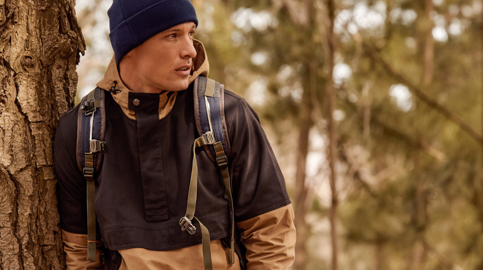 Man with STIHL jacket, beanie and backpack in a forest.