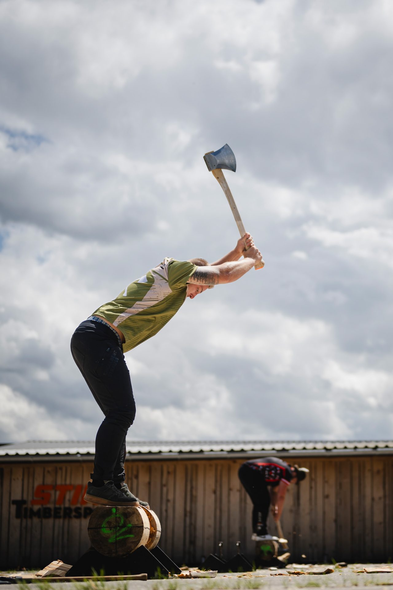 Zwei Athleten auf dem STIHL TIMBERSPORTS Stützpunkt in Mellrichstadt bei der Disziplin Underhand Chop. Die Disziplin simuliert das zerteilen eines bereits gefällten Baumes mit der Axt, während die Sportler auf dem Stamm stehen.